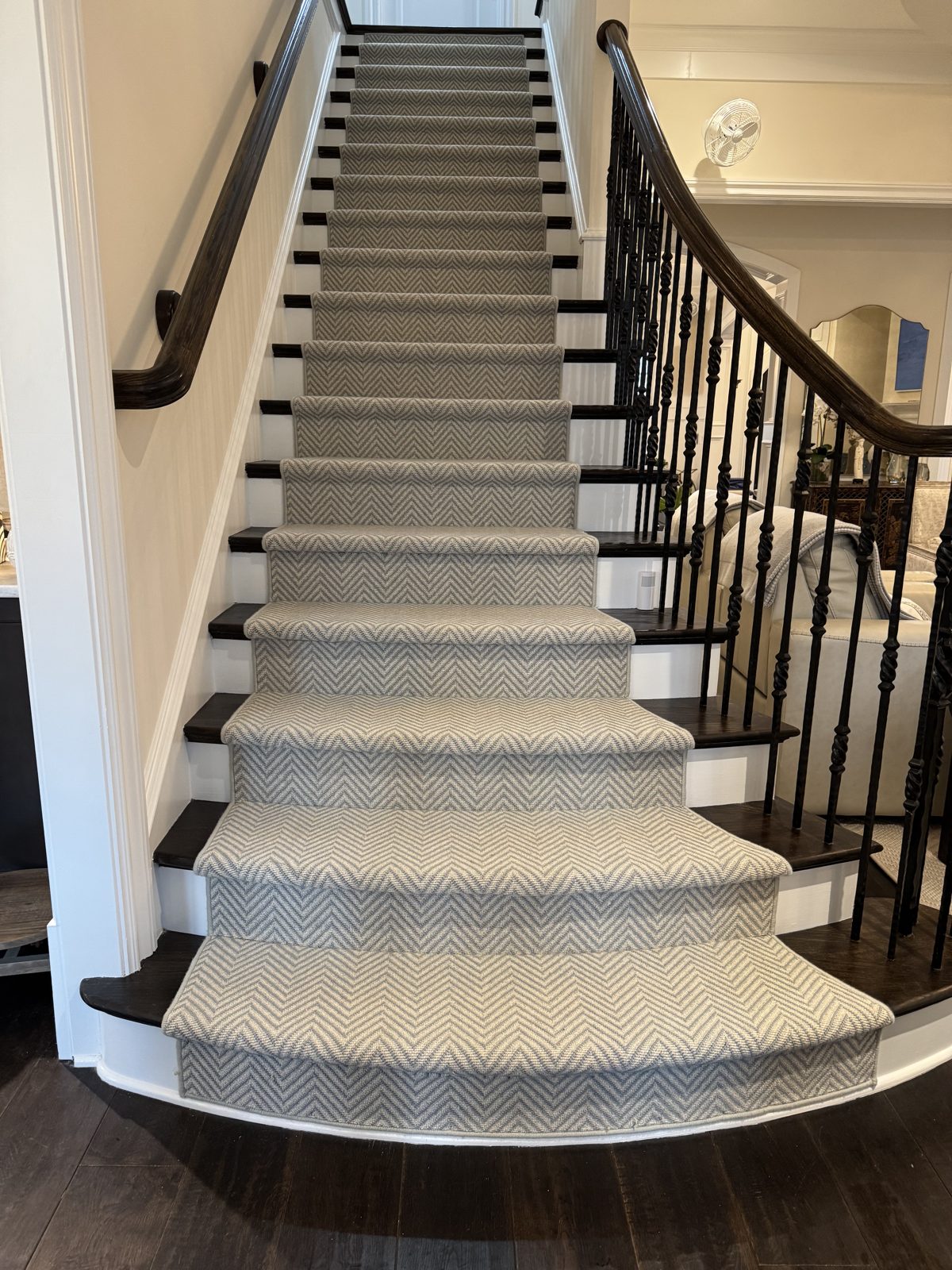 Grand curved staircase with a neutral patterned stair runner